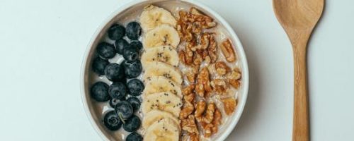 Breakfast Oatmeal with Fruit and Nuts on Top and a Glass of Orange Juice