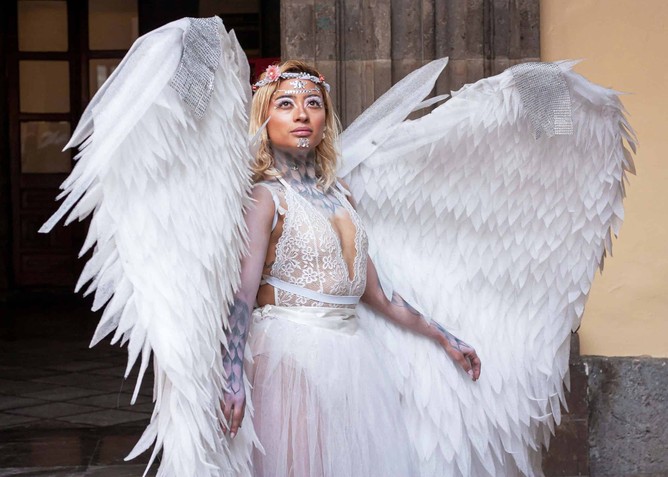 Elegant portrait of a woman in an angel costume with large wings indoors.