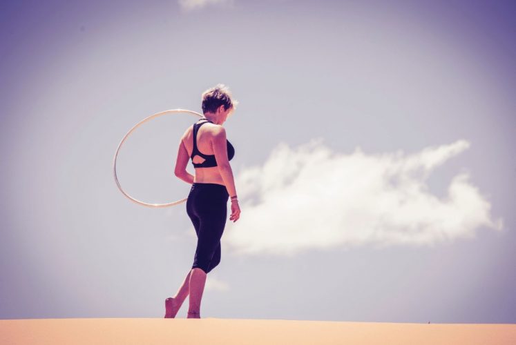 Frau mit Hula Hoop Reifen auf Sand